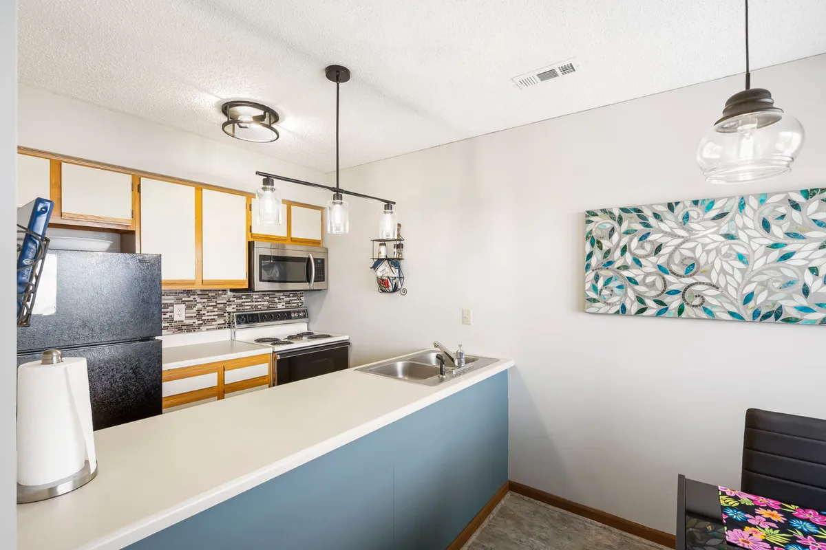 This contemporary kitchen scene showcases a spacious kitchen island, pendant lighting, and a suite of modern appliances. Decorative wall art and a welcoming atmosphere highlight the space's role as a hub for both casual dining and ambitious meal preparation.